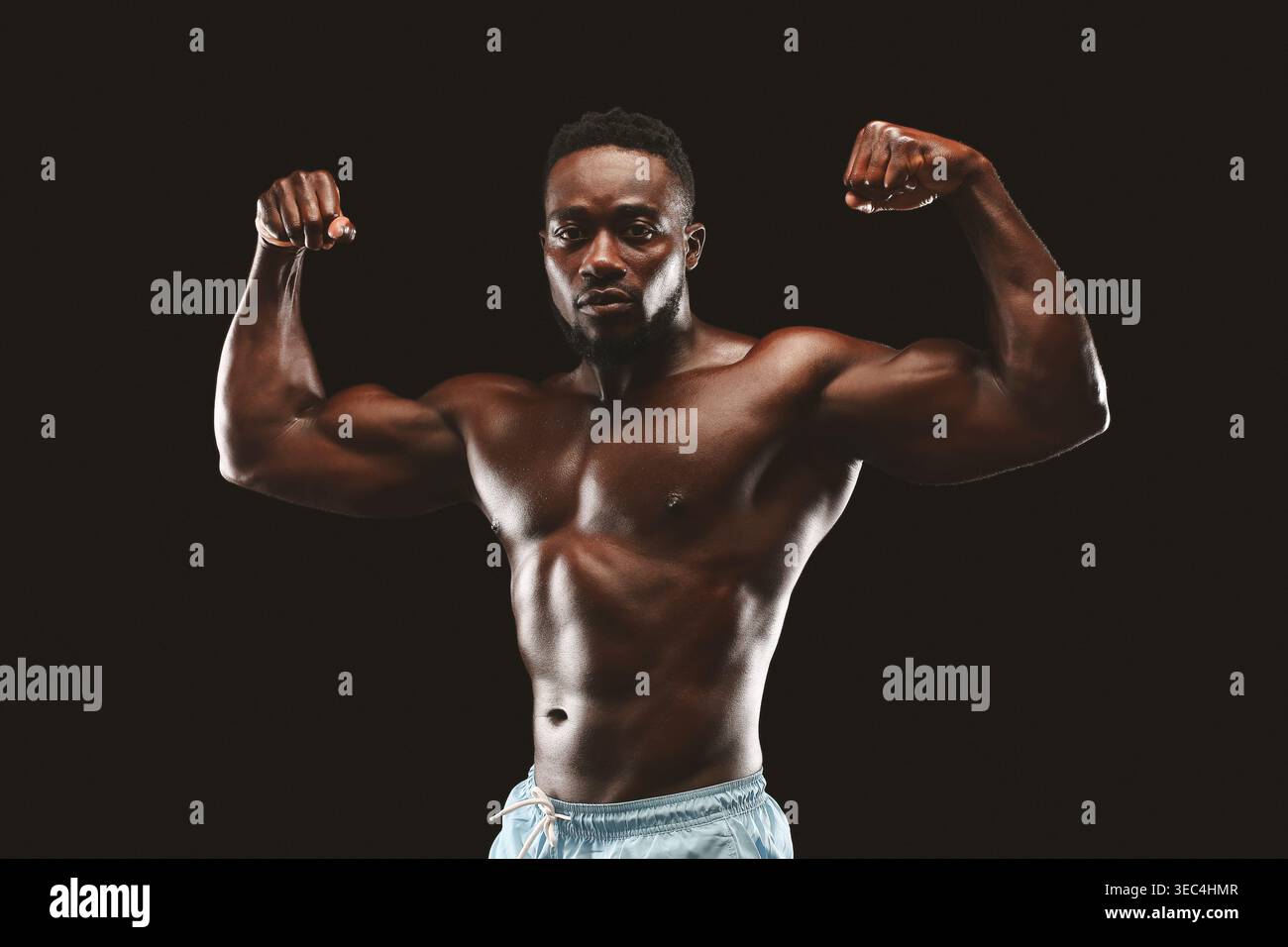 Strong Man fléchit les muscles en mettant en valeur Fitness et force dans Studio Lighting Setup Banque D'Images