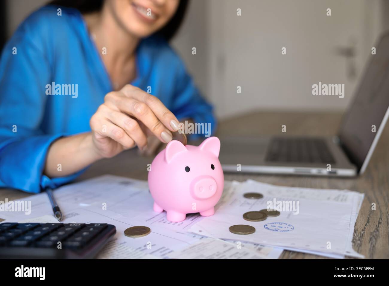 Gros plan d'une femme plaçant des pièces dans une tirelire Banque D'Images