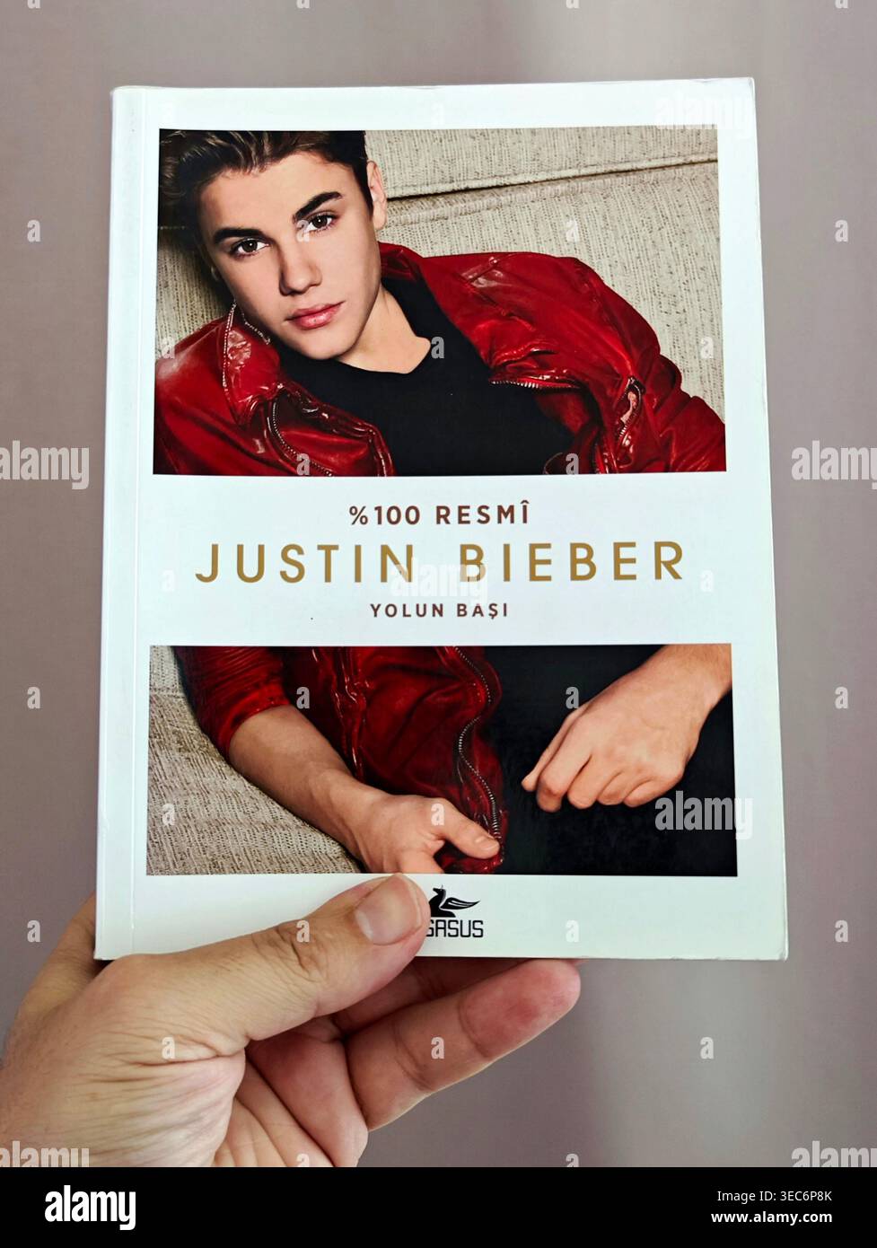 Main tenant le livre '%100 Resmi Justin Bieber : Yolun Başı' de Pegasus Yayınları, avec la couverture de l'édition turque avec un portrait du chant pop Banque D'Images