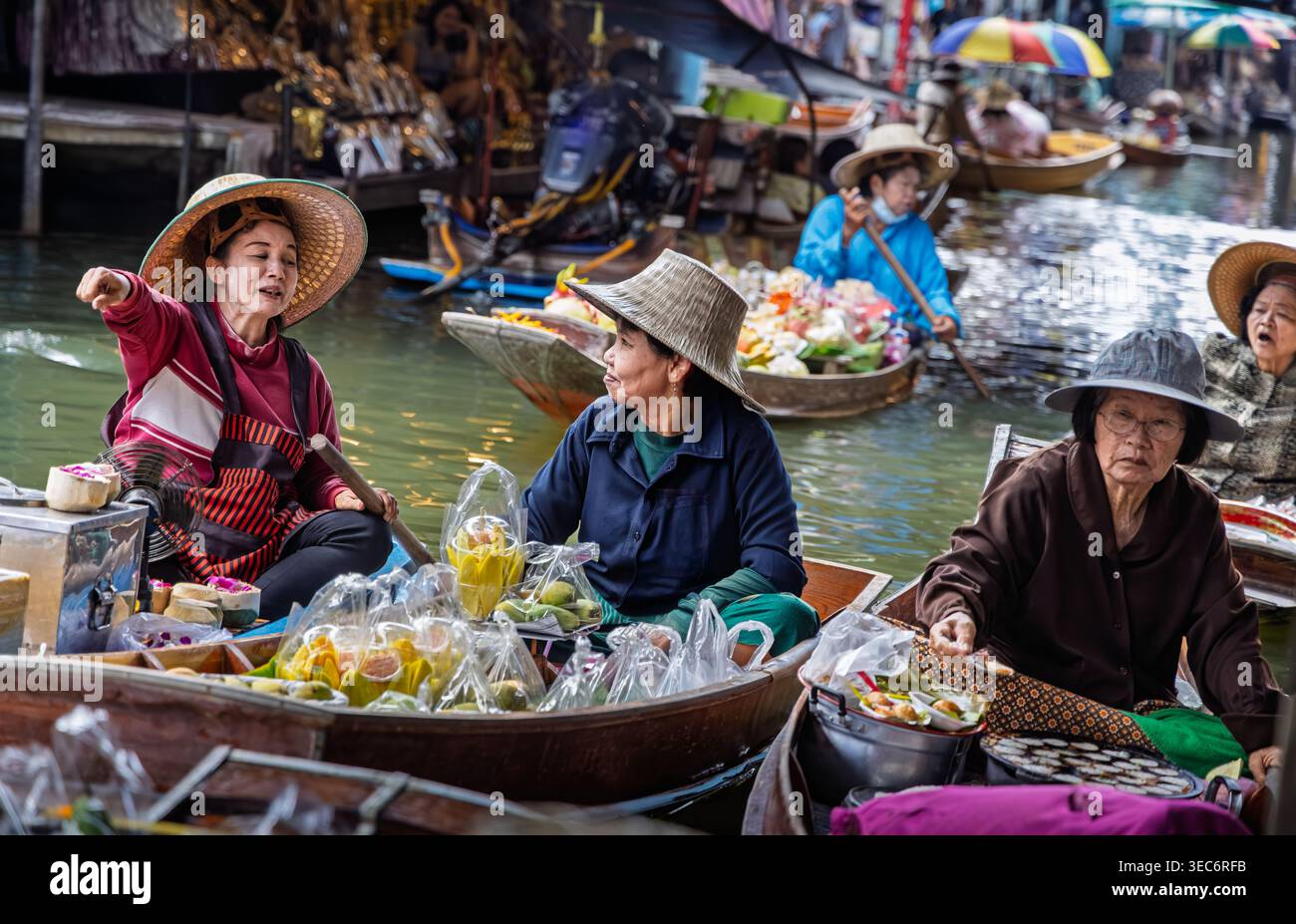 Des vendeuses vendent de la nourriture, des fleurs et des souvenirs de bateaux en bois au Damnoen Saduak Floating Market à Ratchaburi, en Thaïlande Banque D'Images