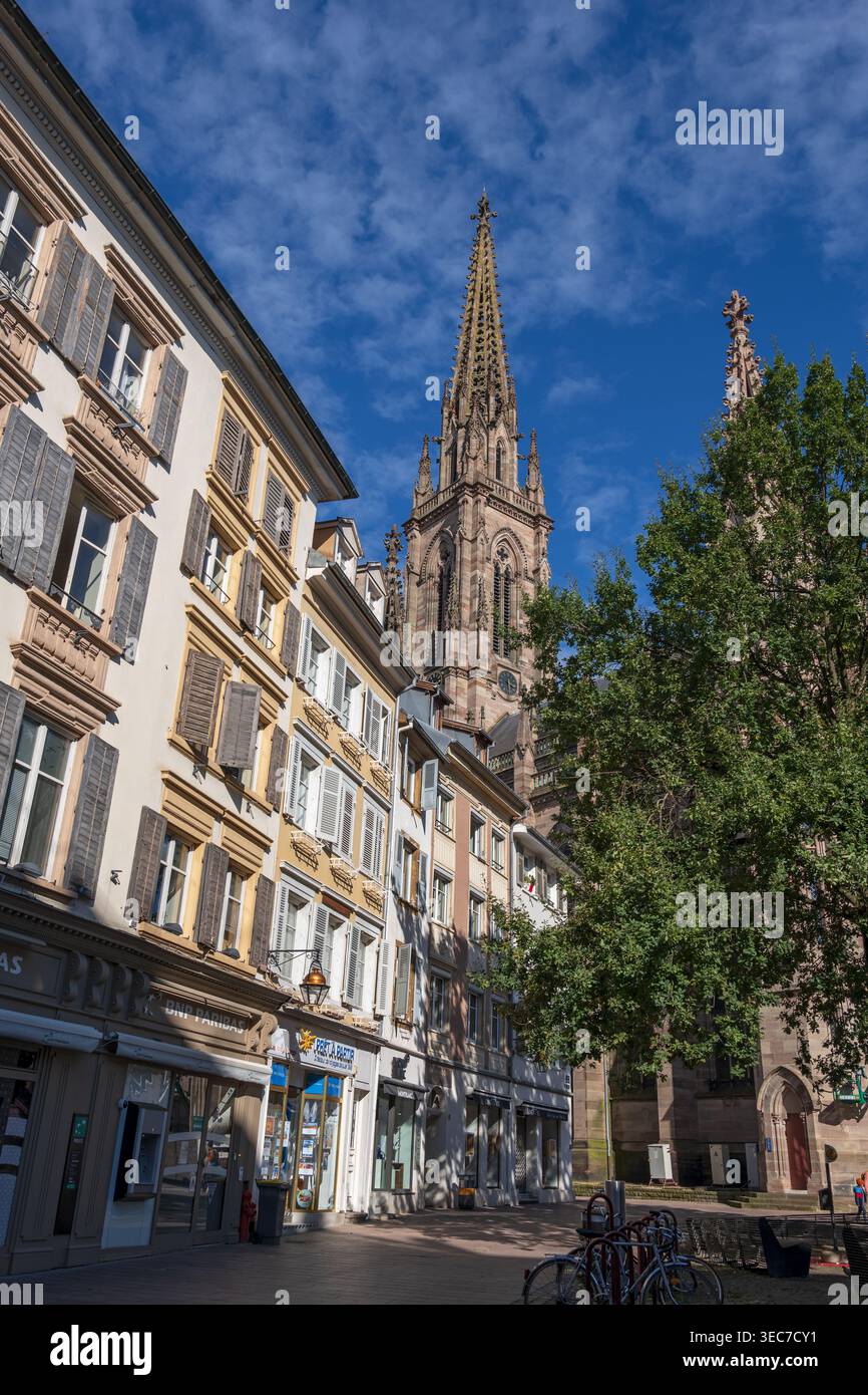 Vieille ville dans la ville de Mulhouse en Alsace, France. Immeubles d'appartements et tour néo-gothique du Temple Saint-Etienne. Banque D'Images