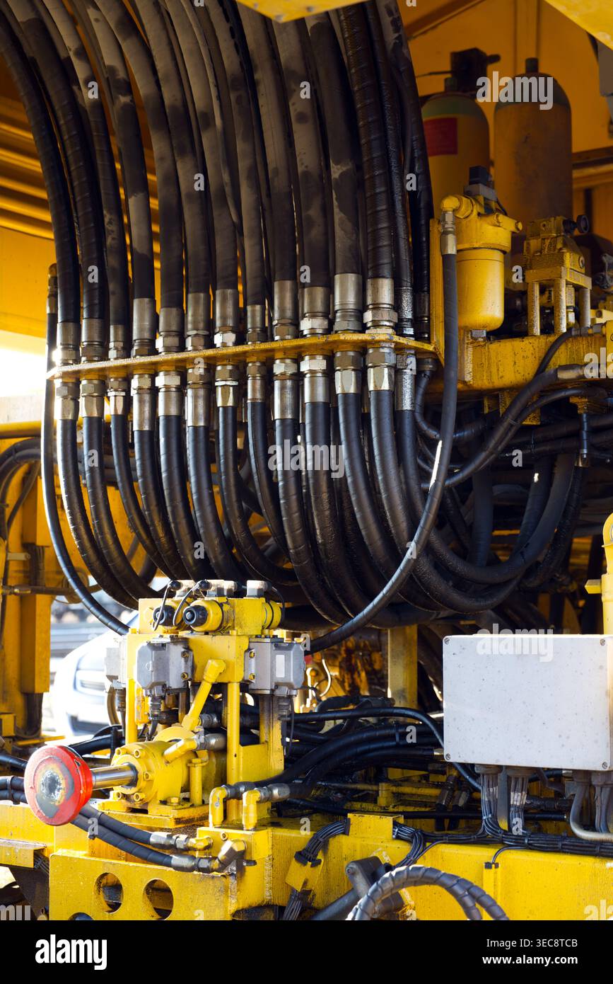 Gros plan détaillé des flexibles hydrauliques extra-robustes et des composants de machines jaunes. Banque D'Images