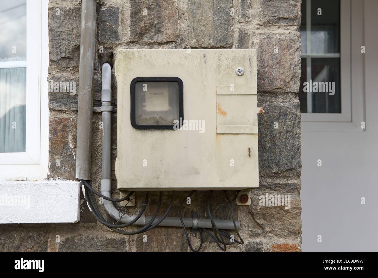 boîte électrique métallique sur mur de pierre grise, fils exposés et tuyaux de conduit, inspection à domicile soft focus et service électrique Banque D'Images