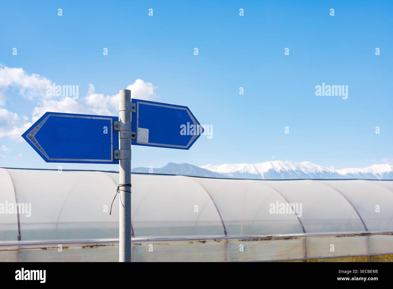 Panneaux directionnels bleus vierges contre les montagnes Banque D'Images