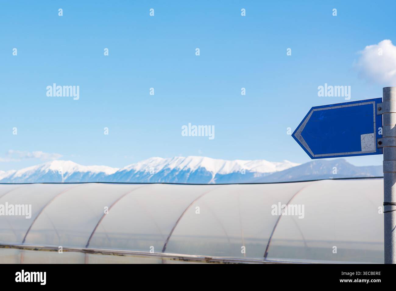 Panneau directionnel bleu vierge contre les sommets enneigés des montagnes Banque D'Images