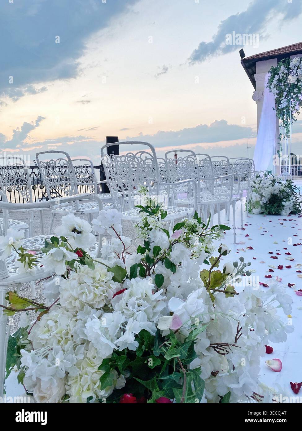 Configuration de cérémonie de mariage avec des fleurs et des chaises par la mer, lumière du coucher du soleil, atmosphère romantique Banque D'Images
