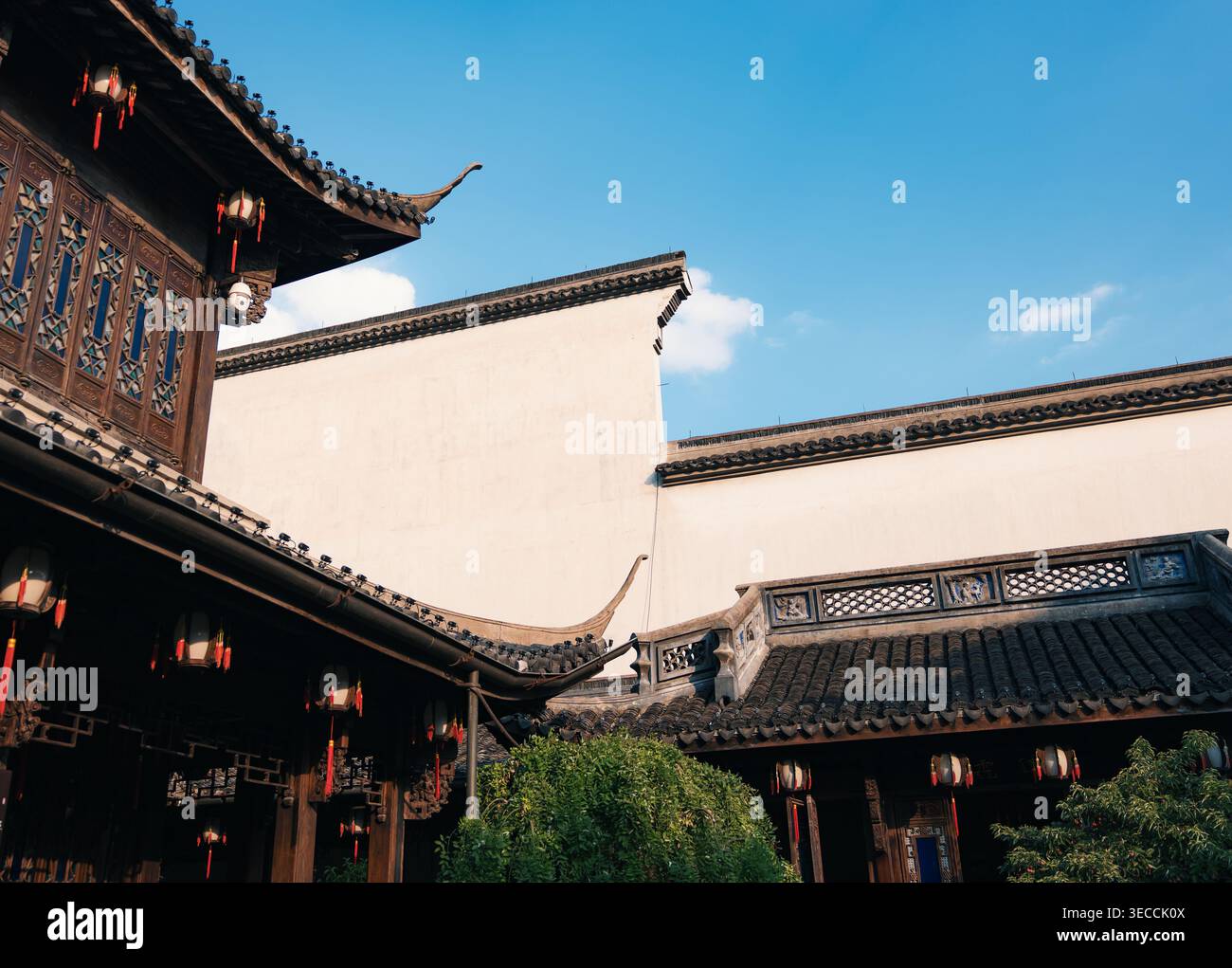 Architecture chinoise traditionnelle avec toits ornés et lanternes rouges sous un ciel bleu clair Banque D'Images
