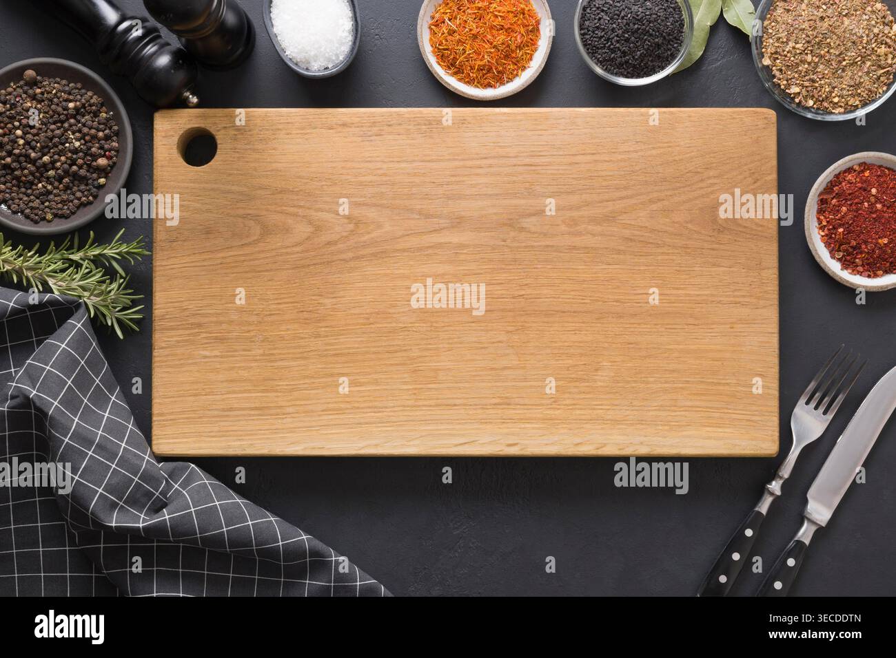 Découpe de planche en bois avec épices et ingrédients pour la cuisson et la marinade de plats savoureux sur noir. Espace pour le texte. Vue de dessus. Banque D'Images