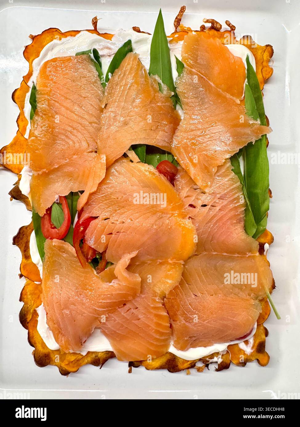 Le plat créatif présente du saumon sur une base de légumes et d'herbes, présenté sur un plateau blanc Banque D'Images