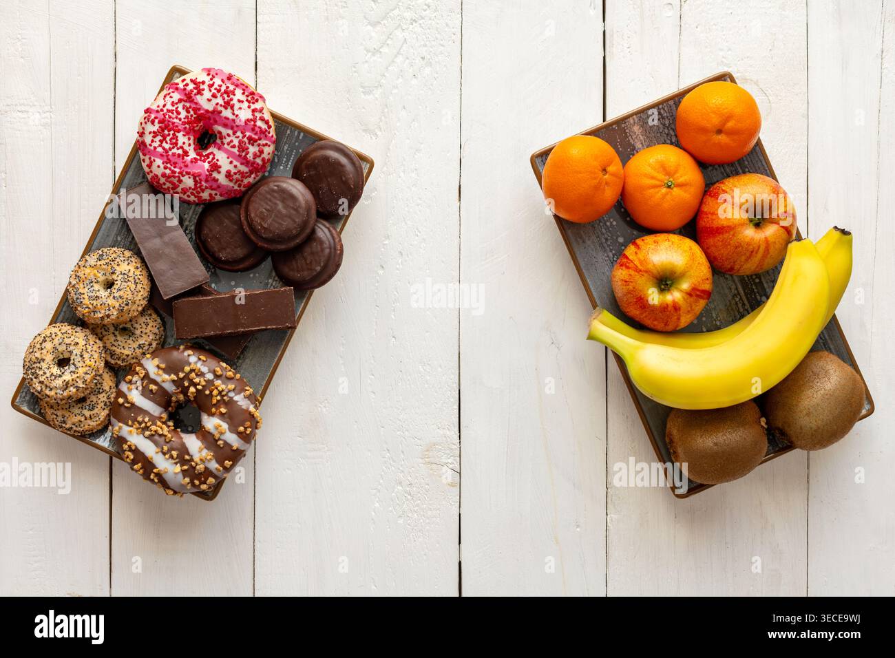 Choix de fruits sains versus collations sucrées. Vue de dessus des fruits frais et des desserts sucrés sur des assiettes séparées, montrant une alimentation saine par rapport à la malbouffe Banque D'Images