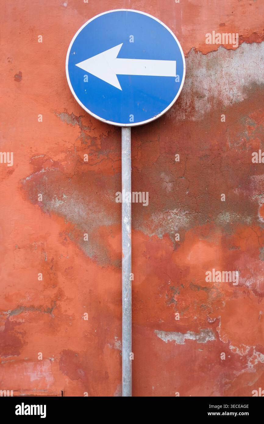 Panneau de système à sens unique à côté d'un mur orange vif en décomposition à Funchal Madère Banque D'Images
