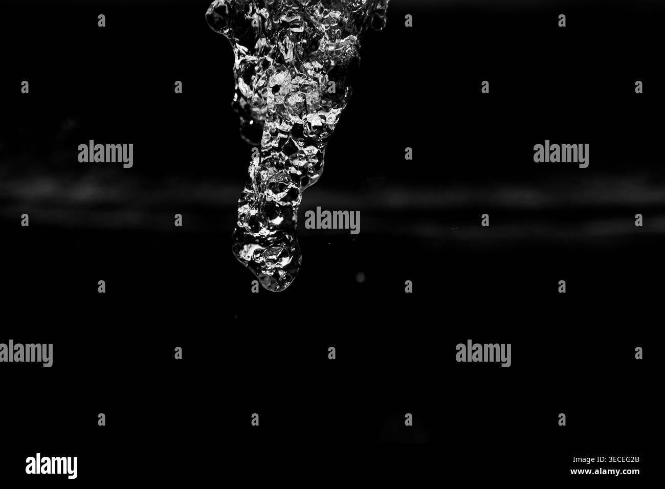 Gros plan d'un courant d'eau transparent tombant sur fond noir pur avec texture éclaboussure dynamique en noir et blanc Banque D'Images