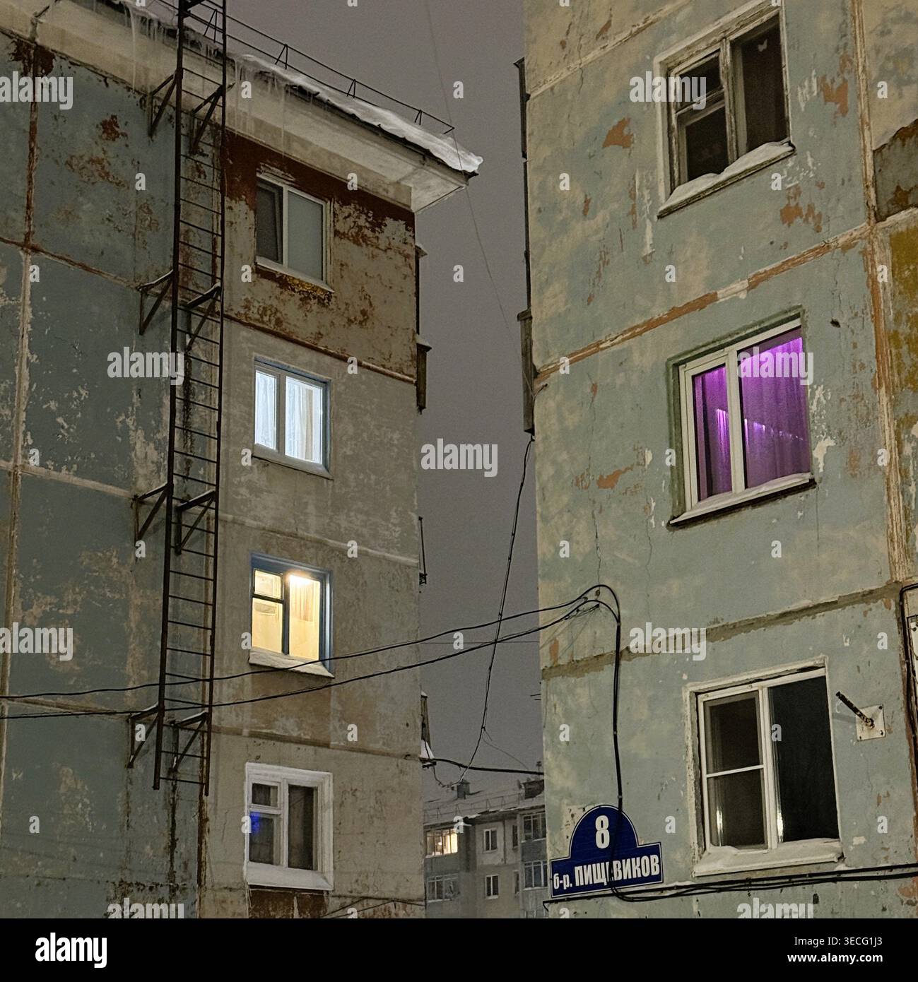 Vieux immeubles d'appartements avec fenêtres éclairées la nuit en hiver Banque D'Images