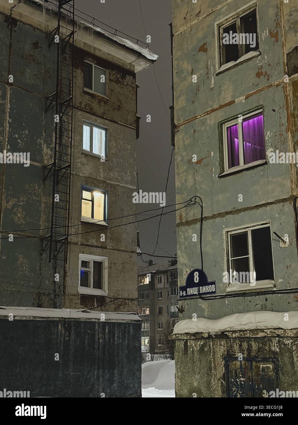 Vieux immeubles d'appartements avec fenêtres éclairées la nuit en hiver Banque D'Images