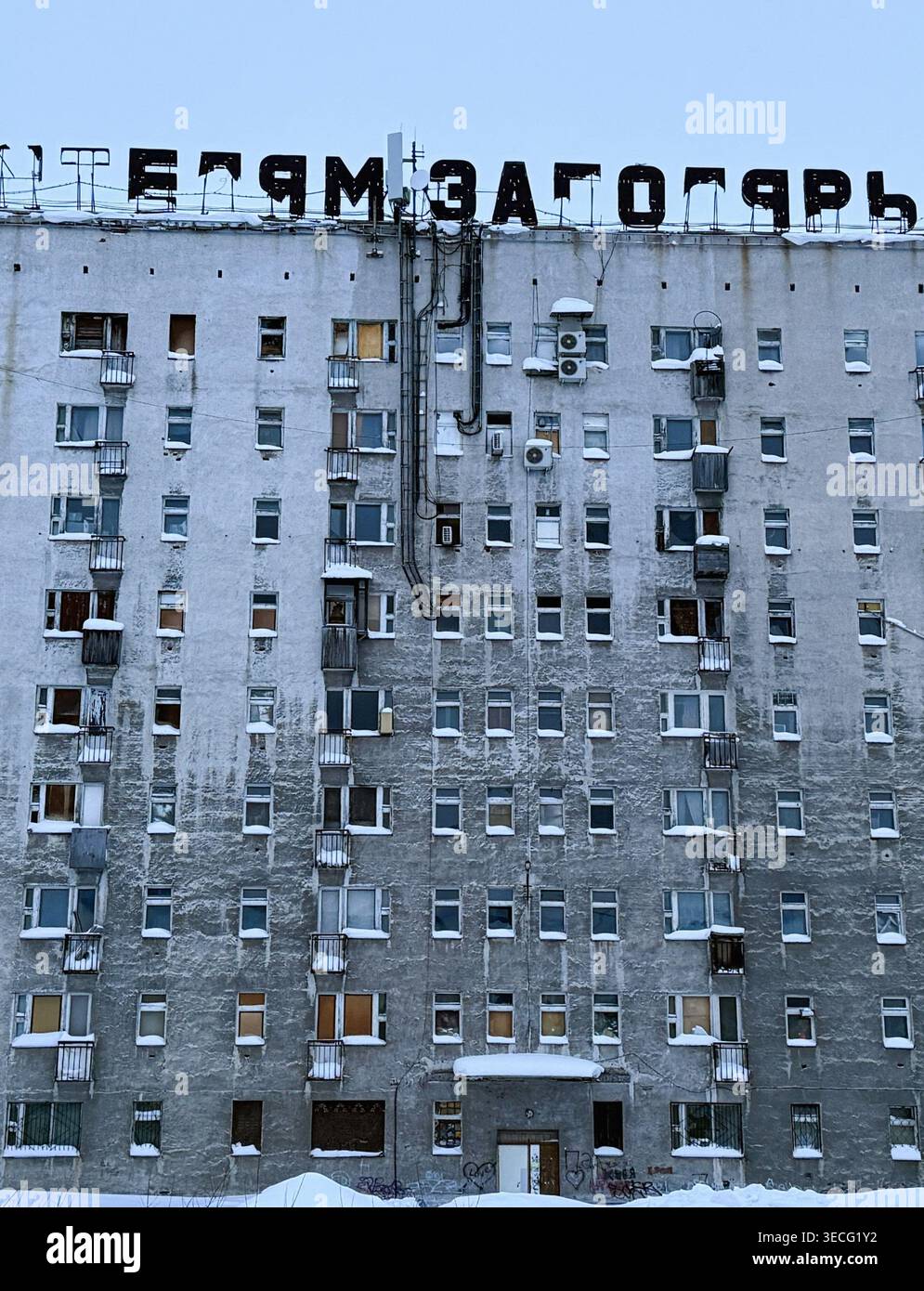 Grand bloc d'appartements soviétiques en hiver avec panneau sur le toit 'Bienvenue tj la ville de gloire' Banque D'Images