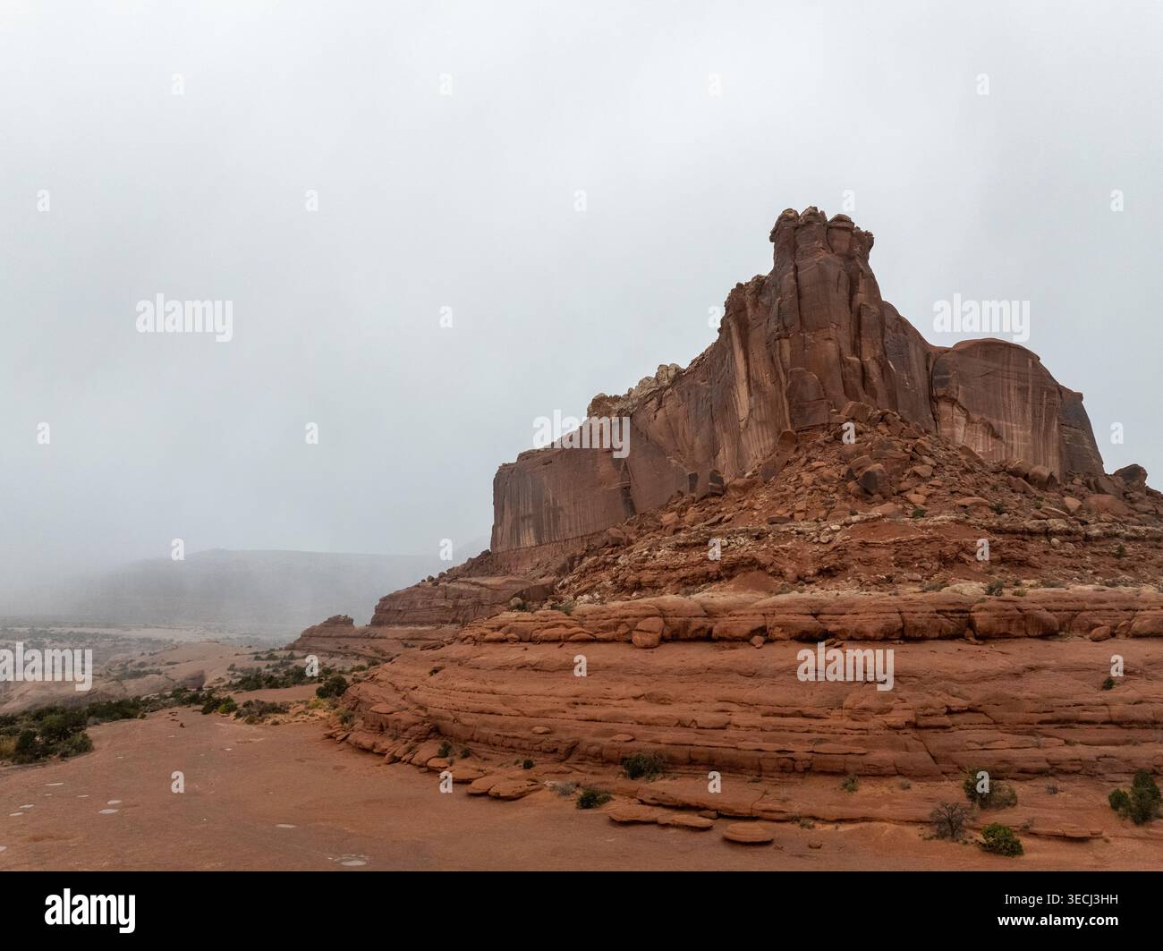 Vue aérienne d'une grande formation rocheuse de grès rouge sous un ciel brumeux et couvert dans l'Utah, USA. Banque D'Images