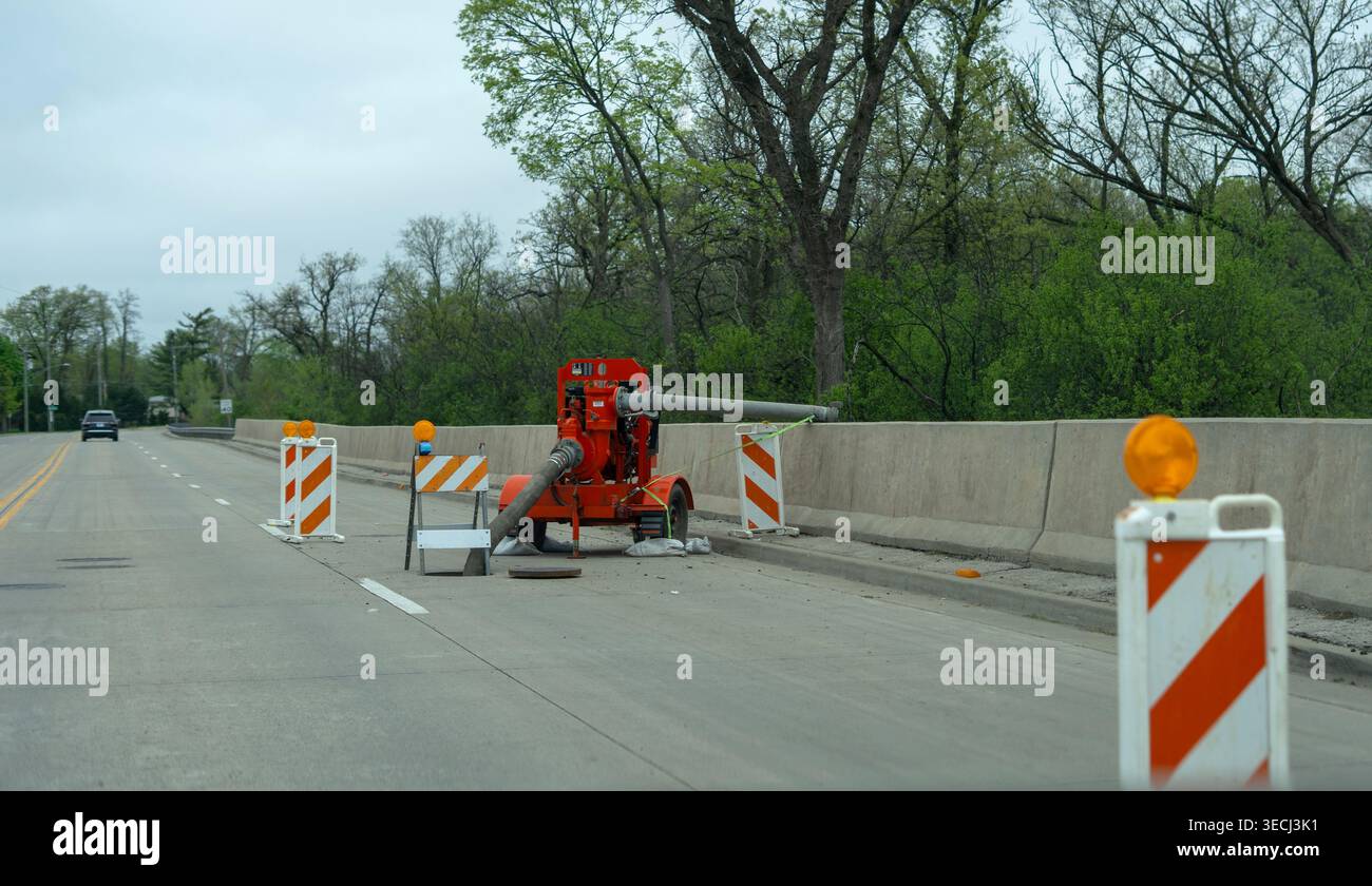 Équipement de pompe de drainage et cônes de sécurité sur la chaussée après de fortes pluies, gestion de l'eau et de l'entretien des routes. Banque D'Images