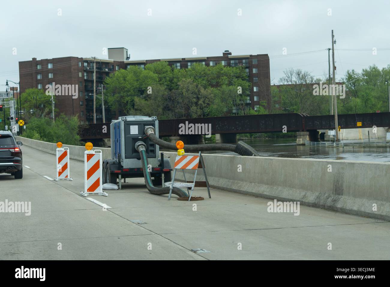 Niveau d'eau élevé près de la rivière avec équipement de pompe de drainage sur la route de la ville après de fortes pluies et des conditions d'inondation. Banque D'Images