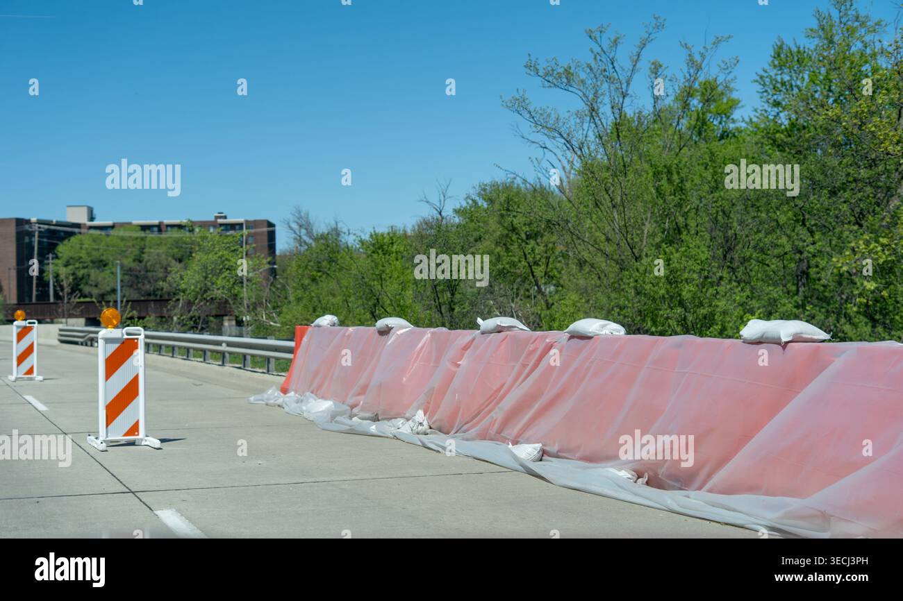 Protection temporaire contre les inondations avec sacs de sable et barrière en plastique le long de la route après de fortes pluies, empêchant les dégâts d'eau. Banque D'Images