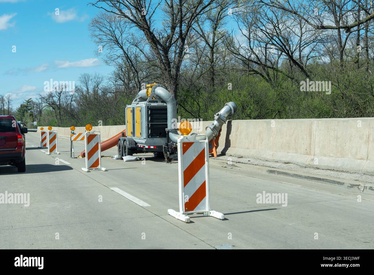Pompe à eau portable et cônes de sécurité sur autoroute après de fortes pluies, gérant le niveau d'eau élevé et le système de drainage. Banque D'Images