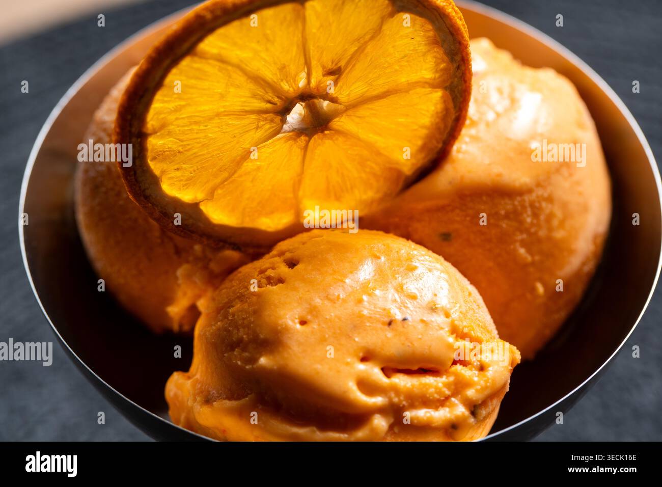 Cuillères à sorbet à l'orange avec tranche d'orange séchée dans un bol foncé Banque D'Images