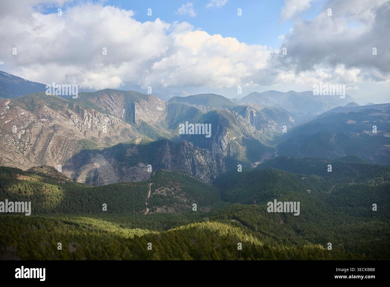 Vue panoramique sur les montagnes Cadi-Moixero en hiver, avec des taches de neige sur les pics accidentés, des vallées stratifiées et une forêt de pins sous les nuages spectaculaires et s. Banque D'Images