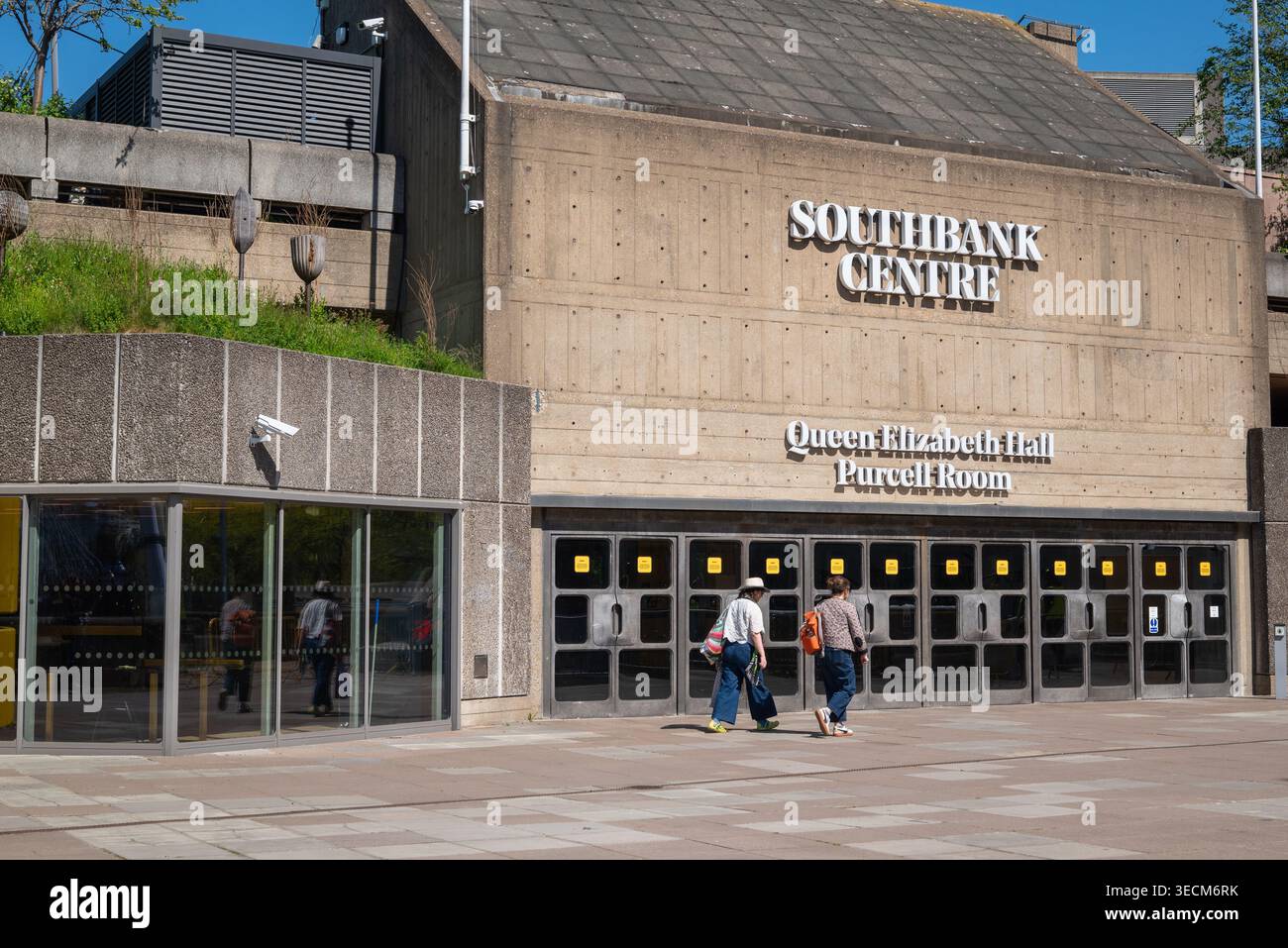 Deux personnes passant devant la salle Purcell Queen Elizabeth Hall au Southbank Centre, Londres SE1, Royaume-Uni. Banque D'Images