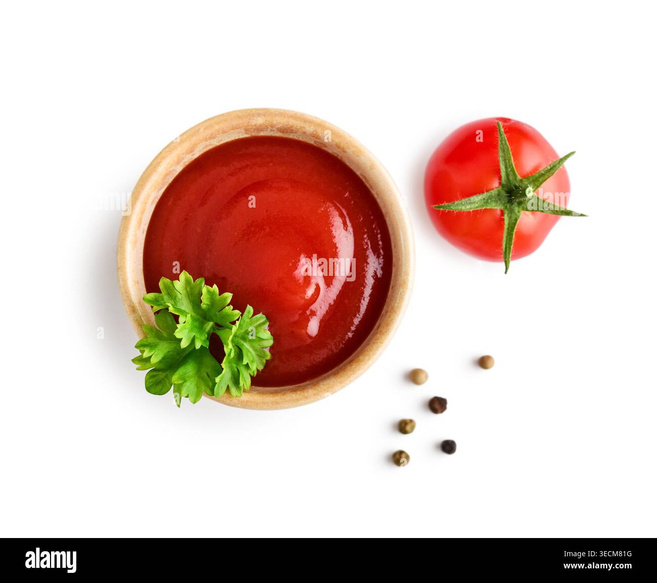 Vue de dessus du ketchup servi dans un petit bol, garni de persil frais et d'une tomate cerise. La scène est isolée sur un fond blanc avec clippin Banque D'Images