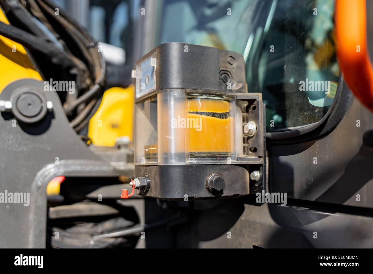 Réservoir du système de lubrification automatisé rempli de graisse orange sur les machines lourdes industrielles, représentant la maintenance préventive et l'ingénierie mécanique Banque D'Images