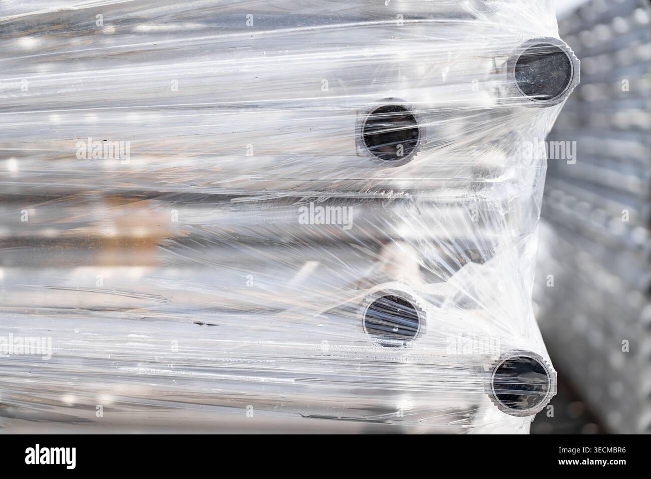 Tuyaux métalliques industriels solidement groupés dans un film plastique extensible transparent pour la logistique et l'expédition mondiale, représentant la gestion de la chaîne d'approvisionnement et Banque D'Images
