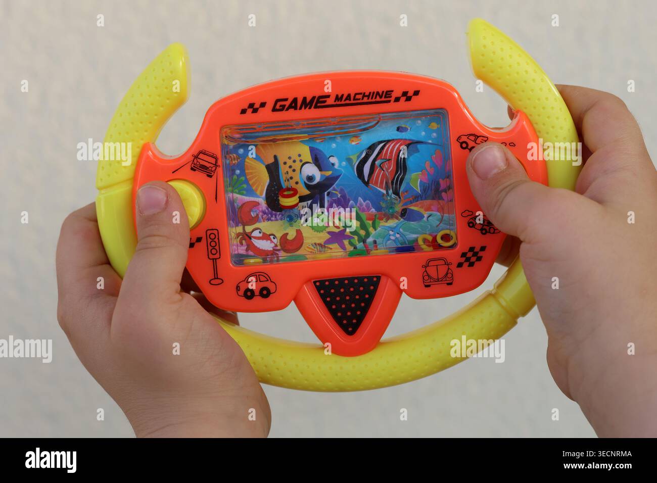 Gros plan des mains d'un enfant jouant avec un jeu de lancer de bague d'eau. Banque D'Images