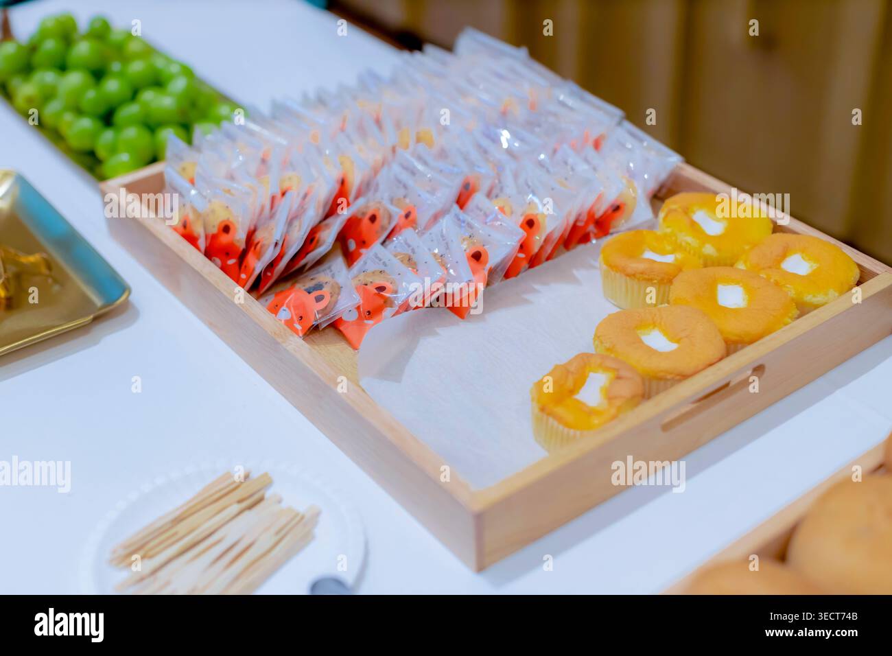 Une table de buffet de collations de traiteur avec de petits cupcakes, des biscuits sucrés emballés et des raisins verts frais pendant une pause café d'un séminaire d'entreprise à Bangkok. Banque D'Images