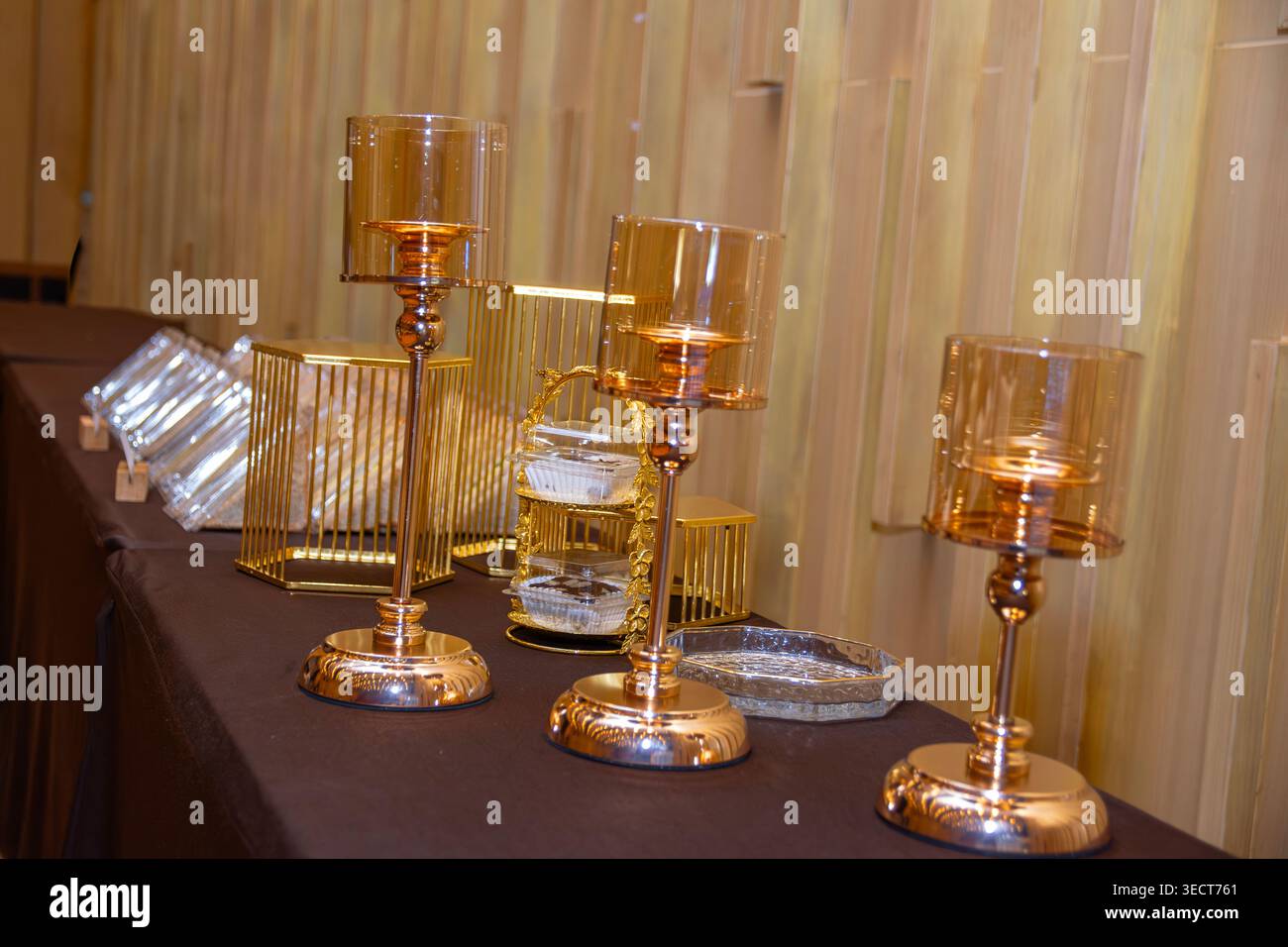 Candélabres en verre doré de luxe et supports à gâteaux géométriques sur une table de buffet d'hôtel. Banque D'Images