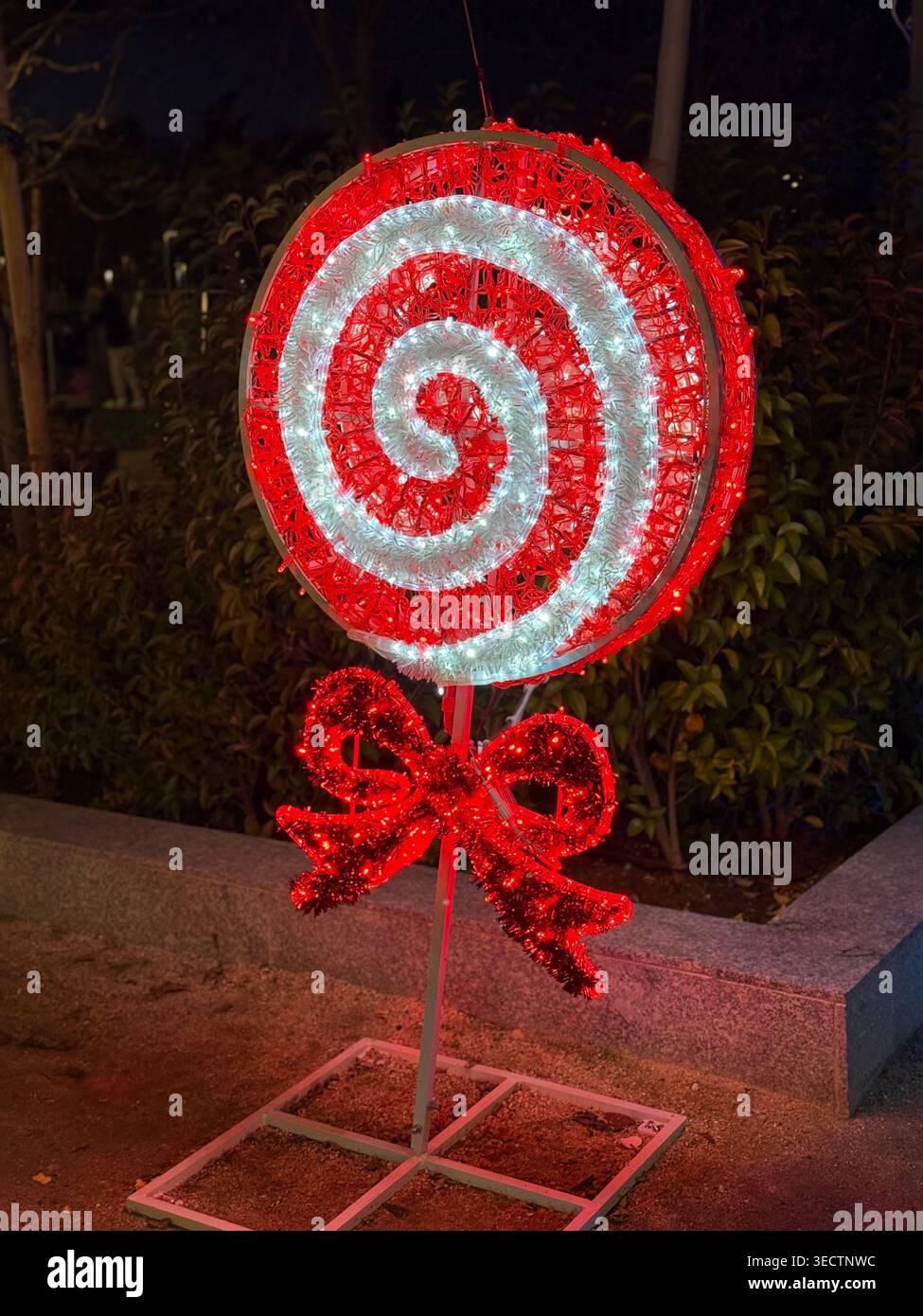 Une photographie nocturne détaillée en gros plan à Madrid capture une installation lumineuse de Noël en forme de canne à bonbons exposée dans un parc public, empha - Image de stock capturée avec un smartphone
