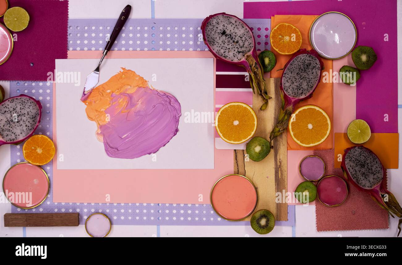 Composition accrocheuse à plat avec des fruits de dragon, des tranches d'agrumes et des kiwis disposés autour d'un fond circulaire rose vif avec espace de copie. Banque D'Images