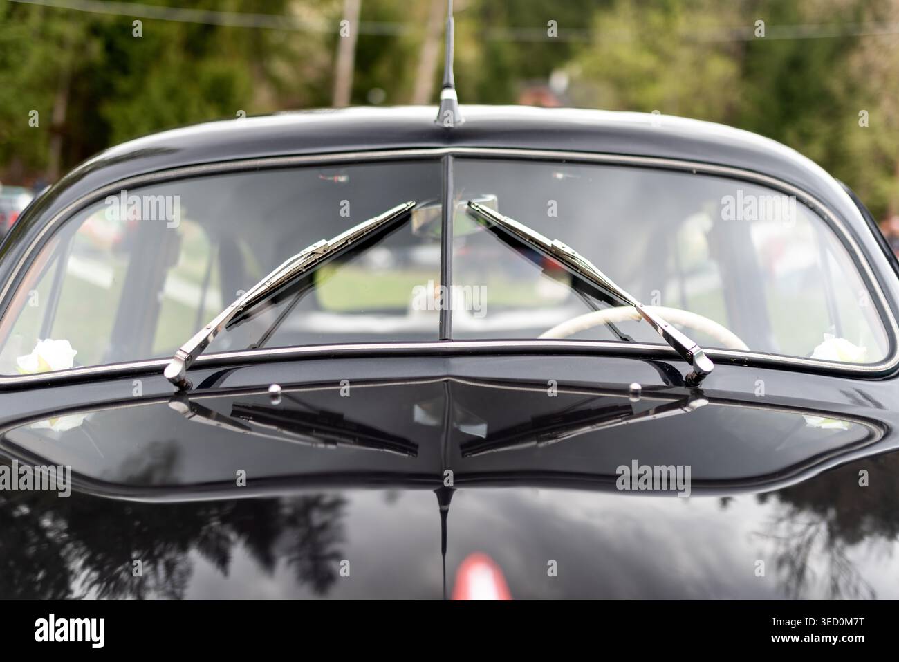 Détail de pare-brise avant de voiture vintage noire avec essuie-glaces symétriques et reflets brillants. Composition automobile rétro minimale avec classique élégant Banque D'Images