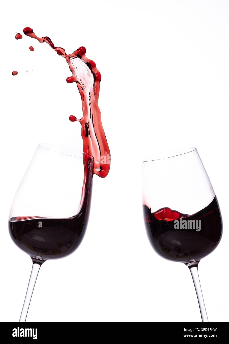Le vin rouge se déverse entre deux verres sur une surface blanche Banque D'Images