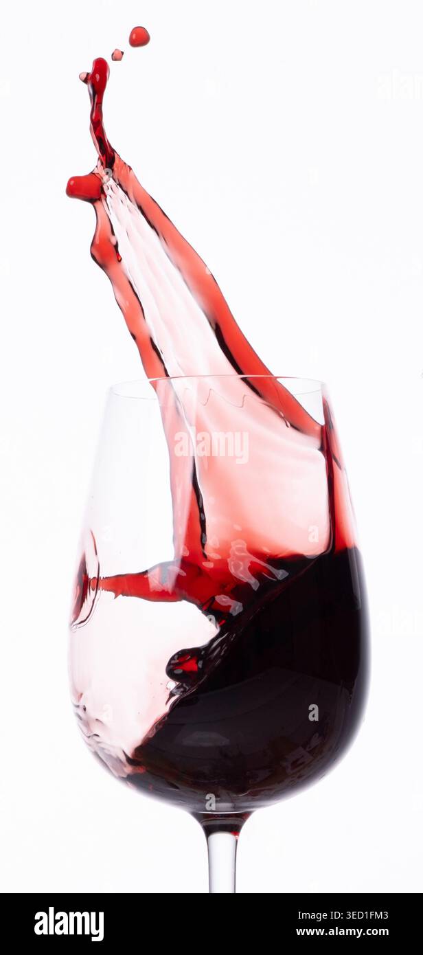 Le liquide rouge crée des éclaboussures dans un récipient en verre transparent Banque D'Images