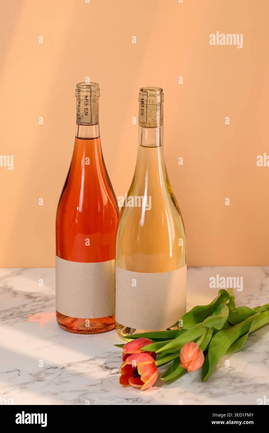 Les bouteilles de vin sont placées à côté des fleurs de tulipe sur une surface de table. Banque D'Images