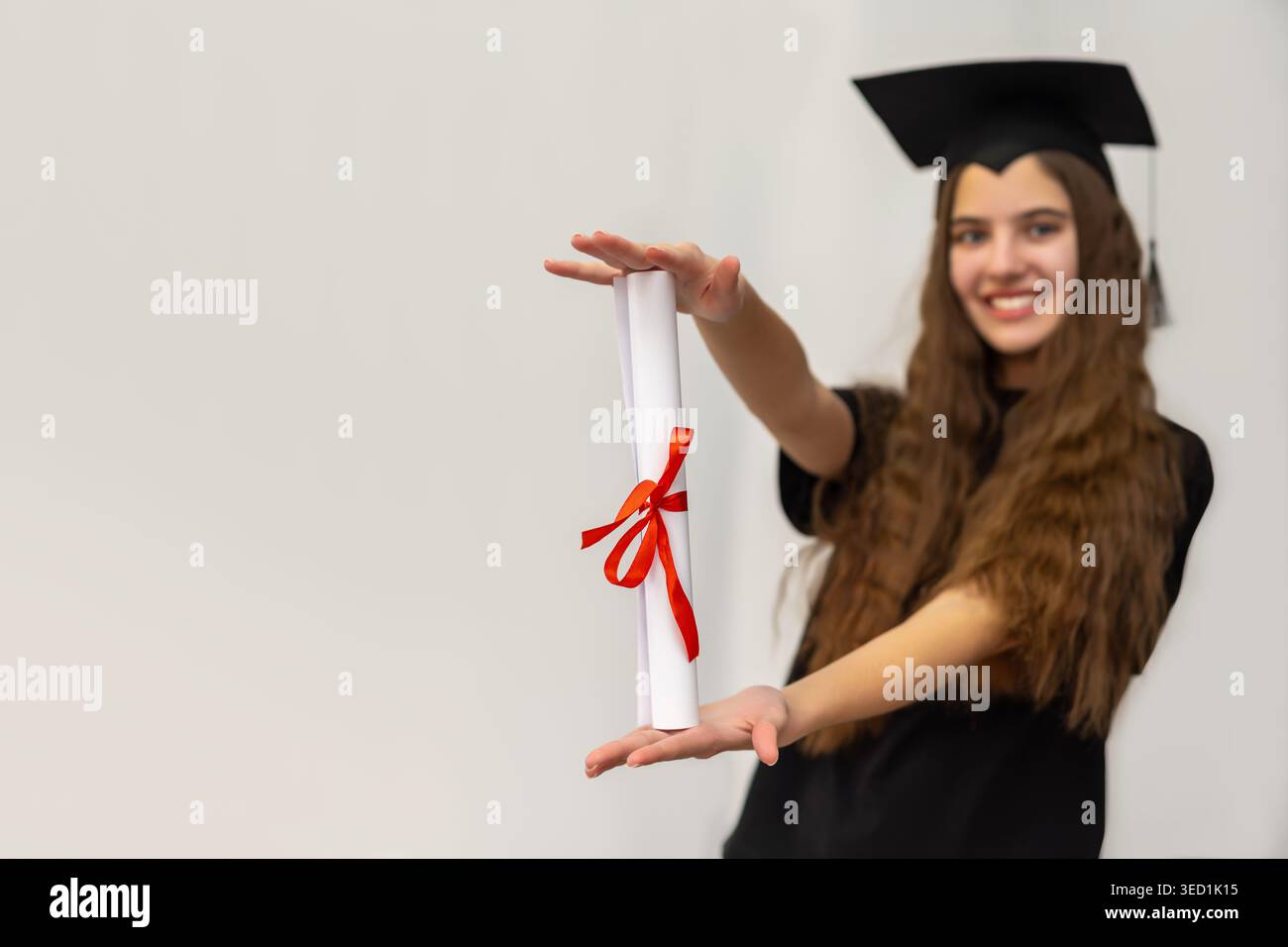 Certificat de diplôme pour diplômé souriant. Jeune femme en casquette de remise des diplômes présentant fièrement un diplôme roulé avec ruban rouge, symbolisant l'éducation Banque D'Images