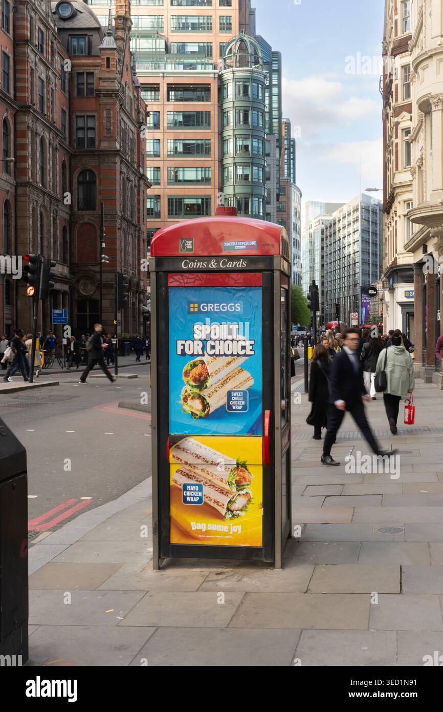 Les gens passent devant une annonce de Greggs sur une cabine téléphonique dans le quartier financier de Londres, Bishopsgate Banque D'Images