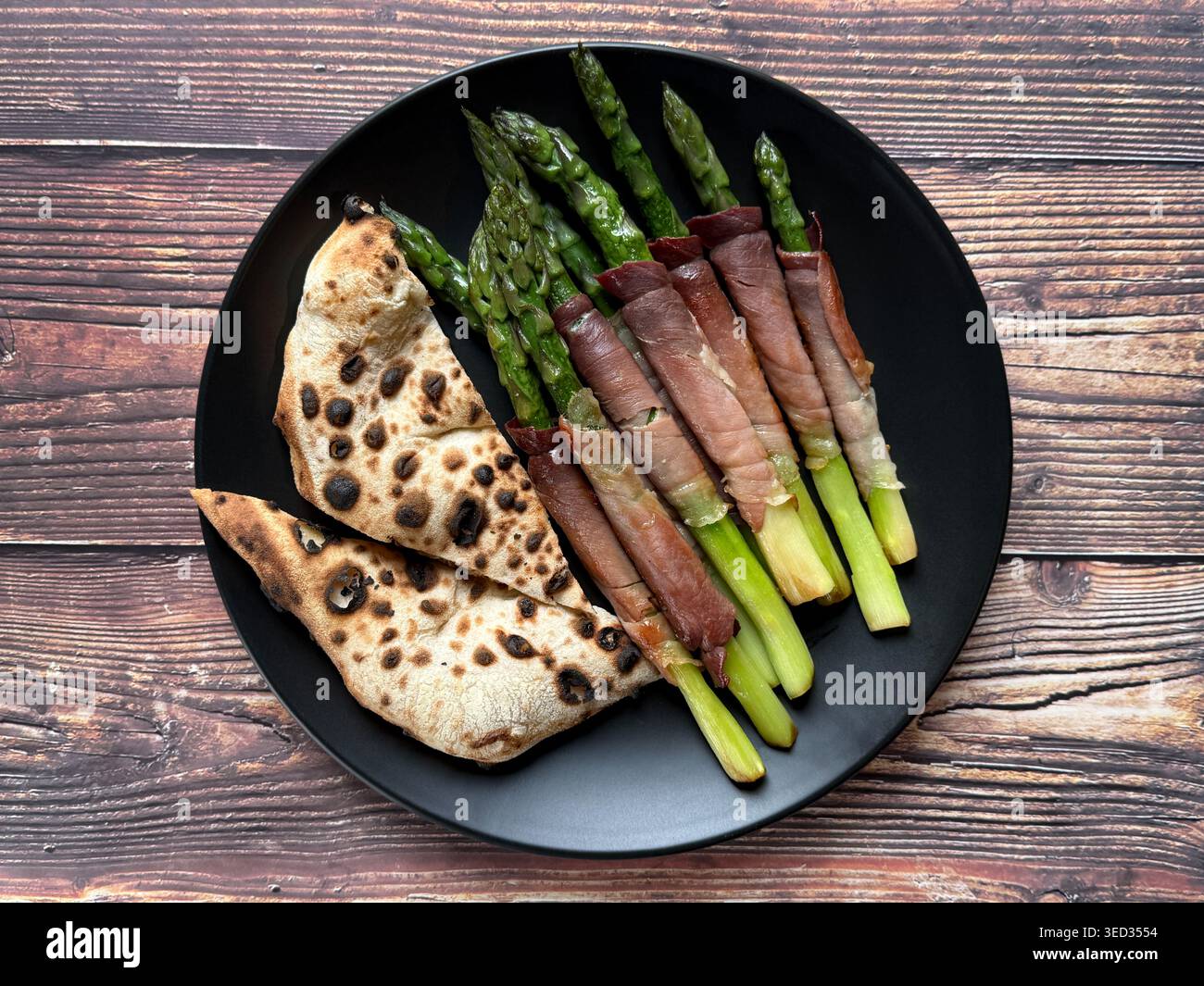 Pizza blanche napolitaine avec asperges, basilic et fromage râpé sur une assiette blanche, vue de dessus sur fond de bois rustique. - Image de stock capturée avec un smartphone