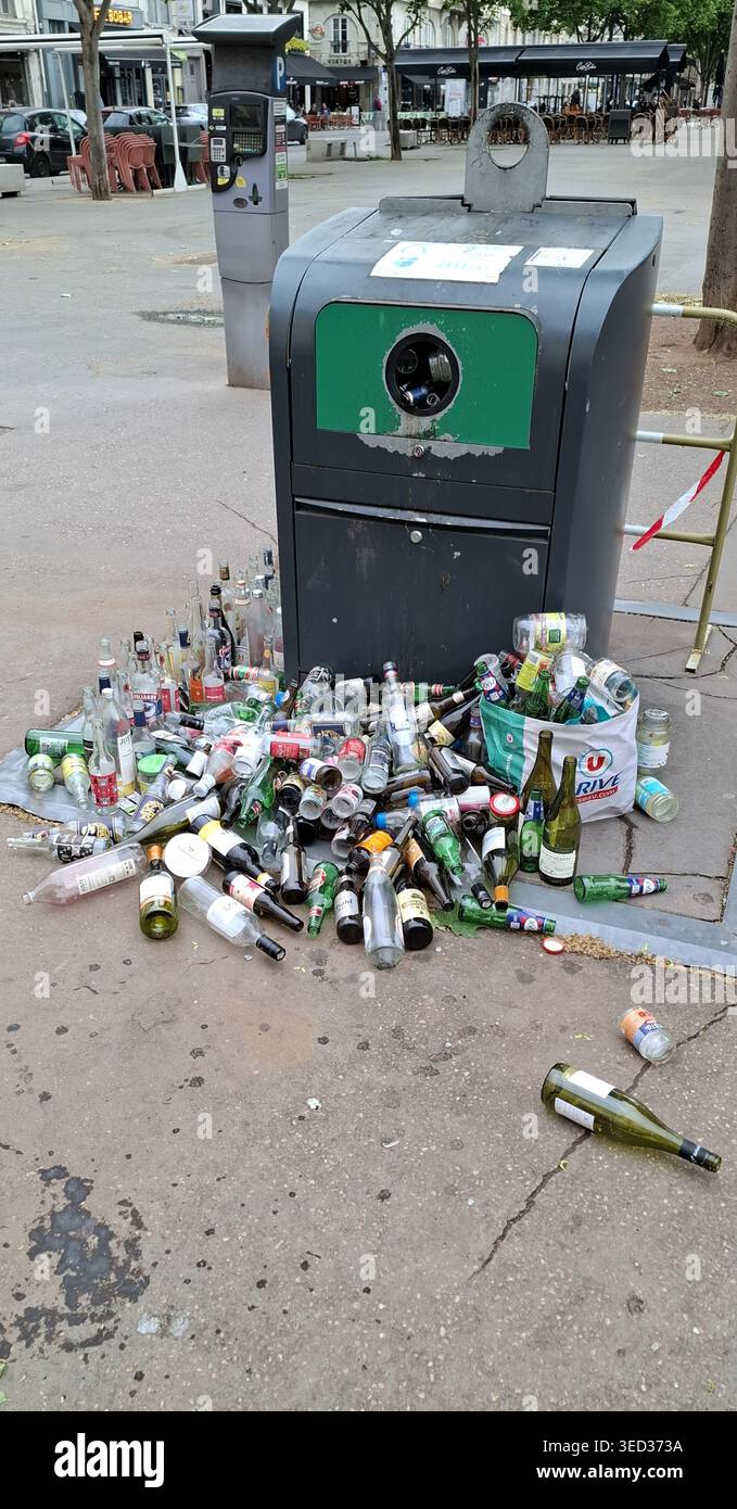 Bac de recyclage en verre débordant avec bouteilles de vin et de bière vides sur une place de la ville à Lyon, France. Banque D'Images