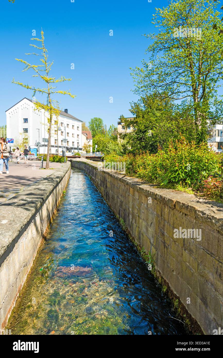 Paderborn, Rhénanie du Nord-Westphalie, Allemagne, 25.04.2026 : rivière claire Pader qui coule en forme de canal à travers la ville avec verdure et chemin piétonnier. Banque D'Images