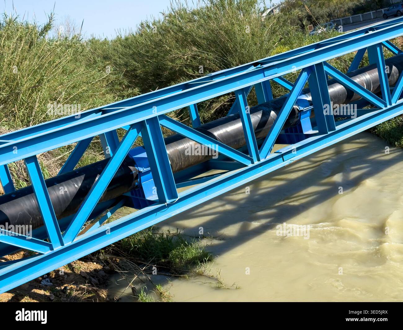 Pont de pipeline industriel au-dessus de l'eau représentant l'infrastructure, le débit et la distribution des ressources Banque D'Images