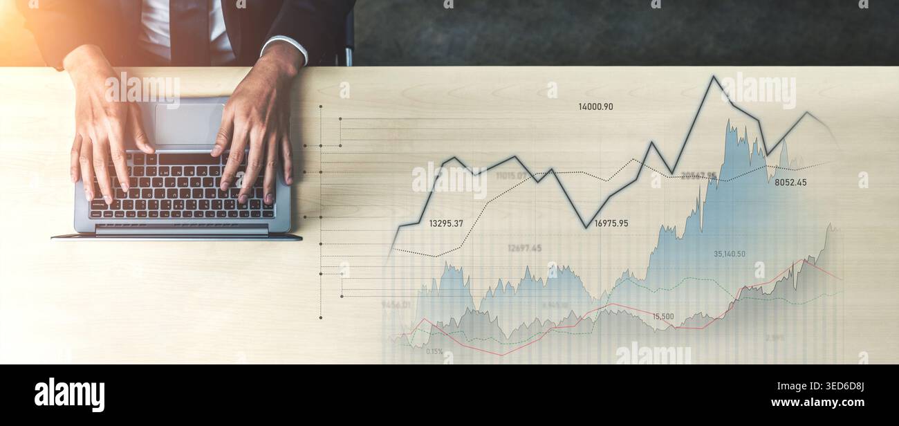 Un homme d'affaires travaille sur un ordinateur portable, analysant les données financières affichées sous forme de graphiques sur un bureau en bois. L'image capture l'essence de l'entreprise moderne Banque D'Images