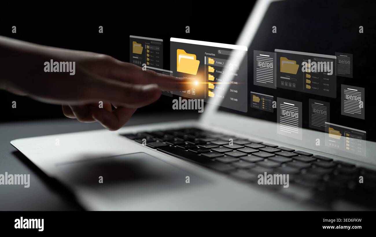 Une vue rapprochée d'une main interagissant avec une interface numérique sur un écran d'ordinateur portable, présentant des dossiers et des fichiers dans un espace de travail moderne, mettant en évidence Banque D'Images