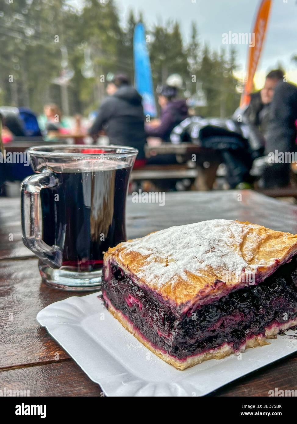 Tarte traditionnelle aux myrtilles avec du sucre en poudre et du vin chaud chaud sur une table en bois à Kopaonik, Serbie. - Image de stock capturée avec un smartphone