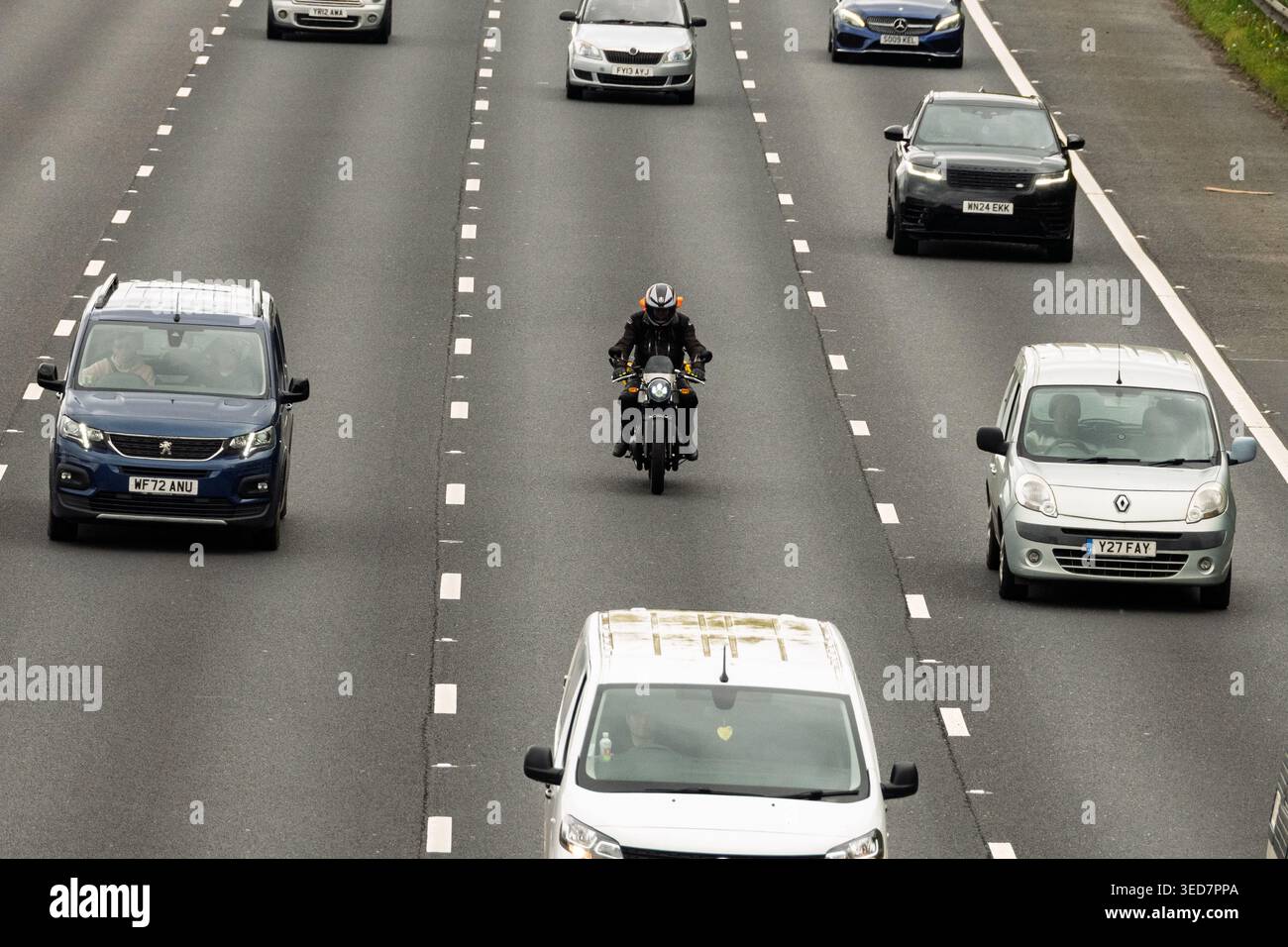 Sur une autoroute M6 nord très fréquentée à Warrington, un motocycliste solitaire tisse habilement à travers un flot de véhicules rapides. Banque D'Images