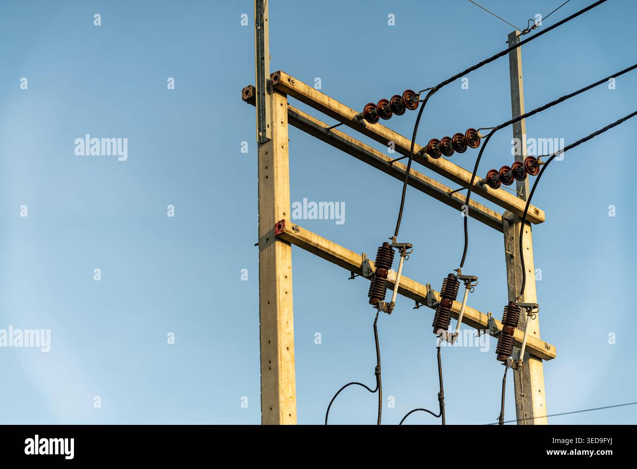 Cette image montre un poteau électrique en bois avec des fils et des isolants contre un ciel bleu clair, mettant en valeur l'infrastructure énergétique et desi de service public Banque D'Images